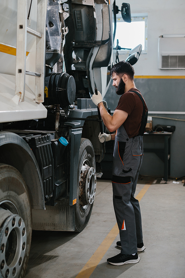 Mechanic repairing truck engine in garage workshop Divi-About-Us-Section-Hero-Image-2